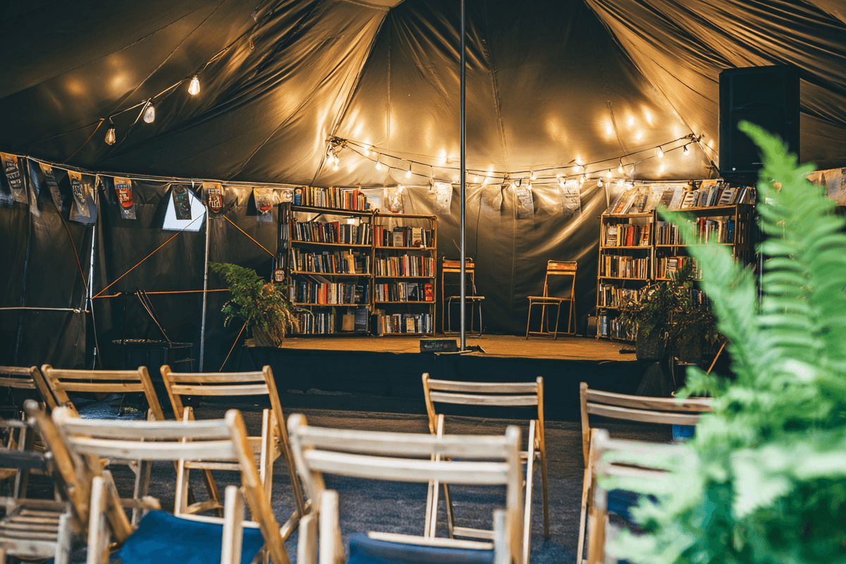 Festival tent with bookshelves, fairy lights, and rows of empty chairs
